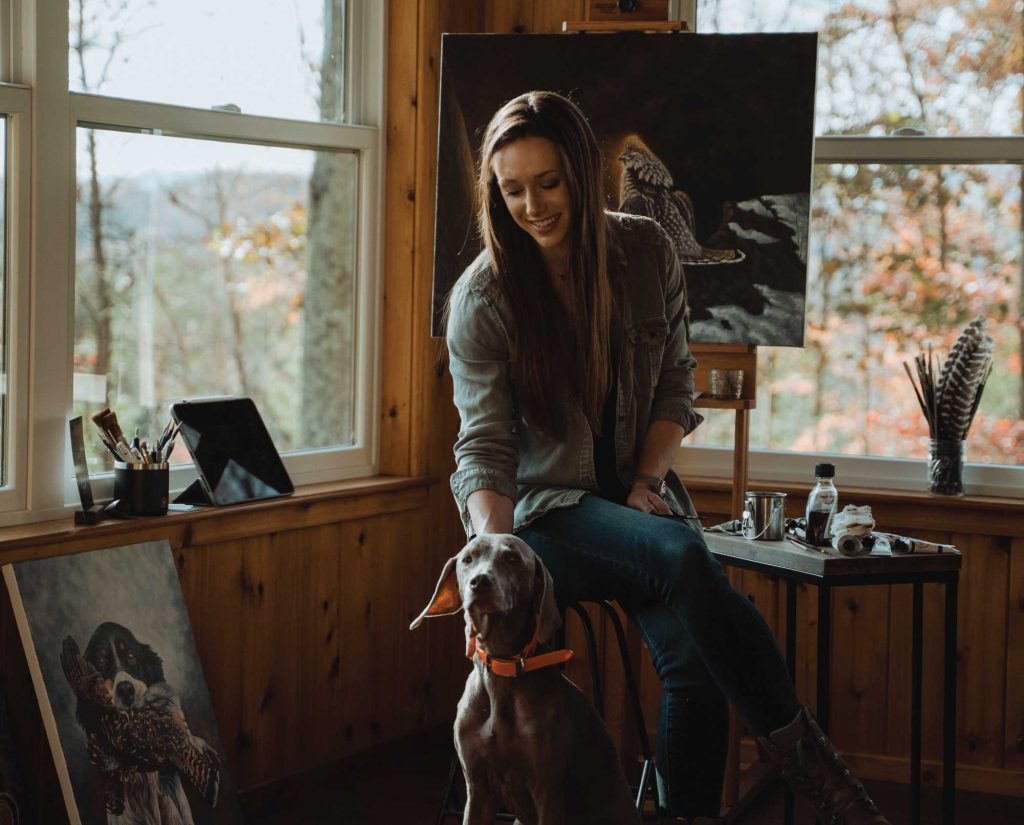 Amanda Ballengee in her art studio with her bird dog.