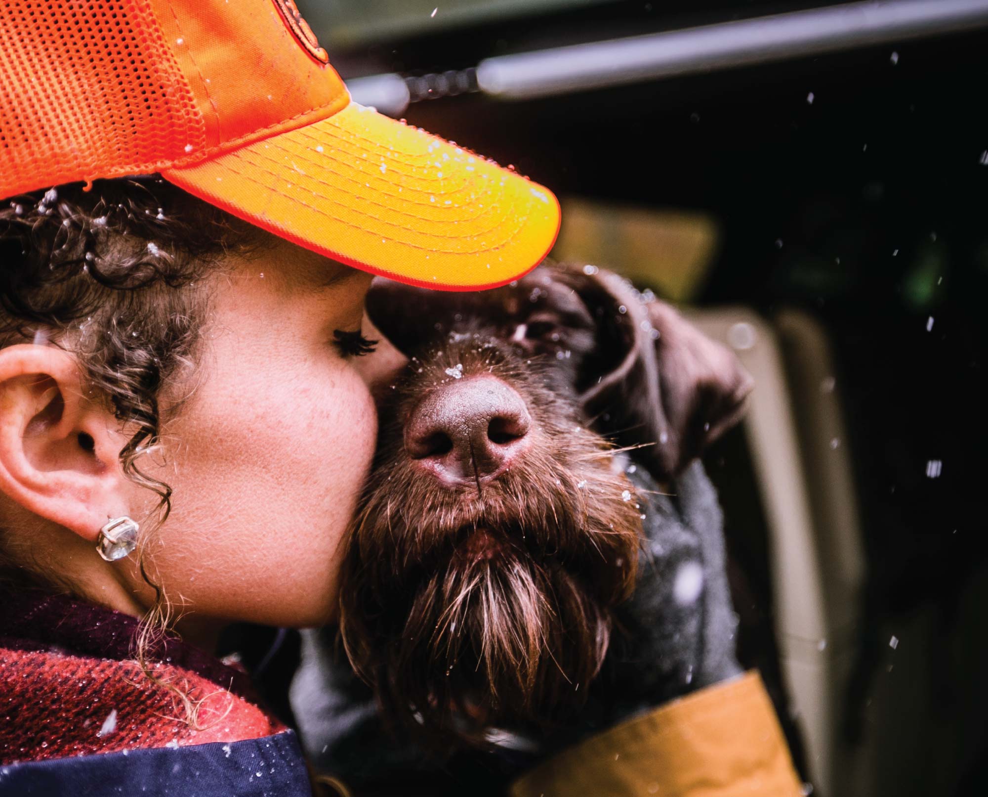 A woman kisses her bird dog.
