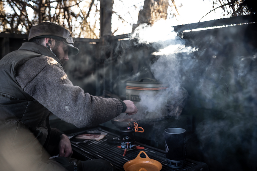 A man cooks breakfast in a duck blind