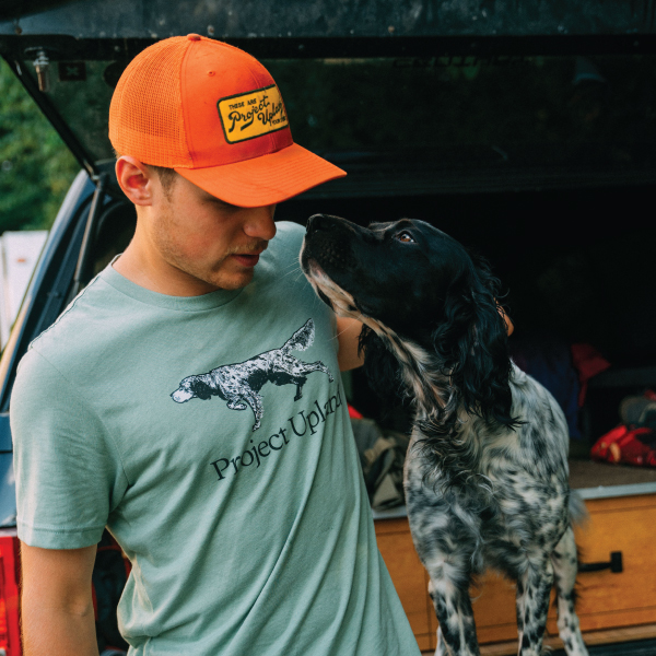 A man wearing English setter merchandise while with his dog.