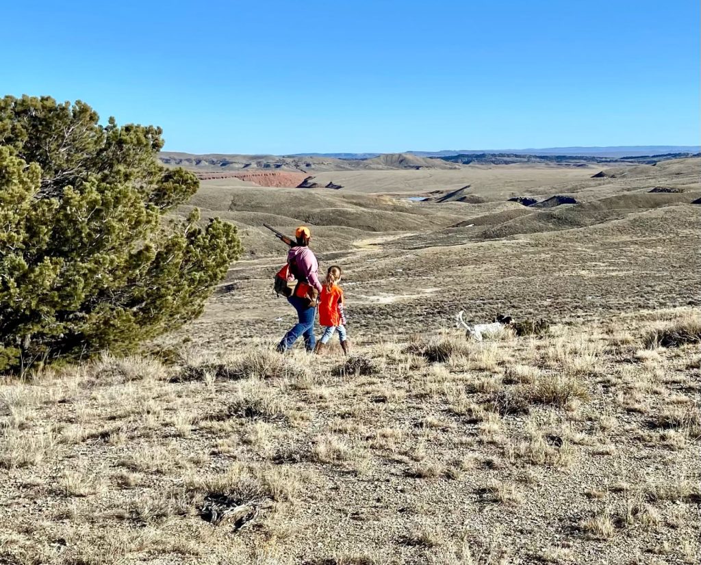 A mother takers her daughter hunting with a dog.