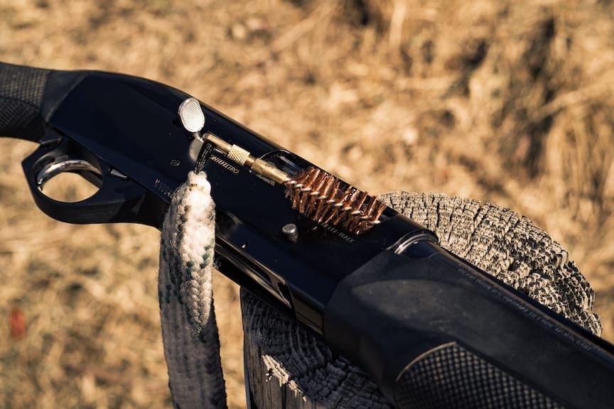 A bore snake being inserted into a shotgun barrel
